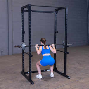 Woman doing a barbell back squat inside the black Best Fitness BFPR100B power rack