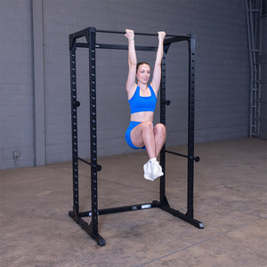 Woman doing hanging knee raises from the pull-up bar of the black Best Fitness BFPR100B power rack