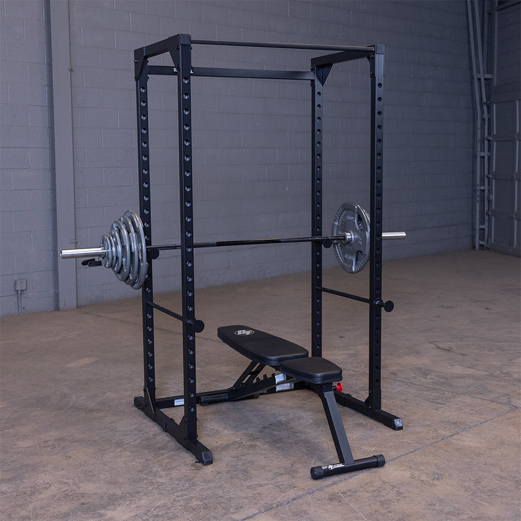 Black Best Fitness BFPR100B power rack with a loaded barbell on the lift-offs and a bench inside