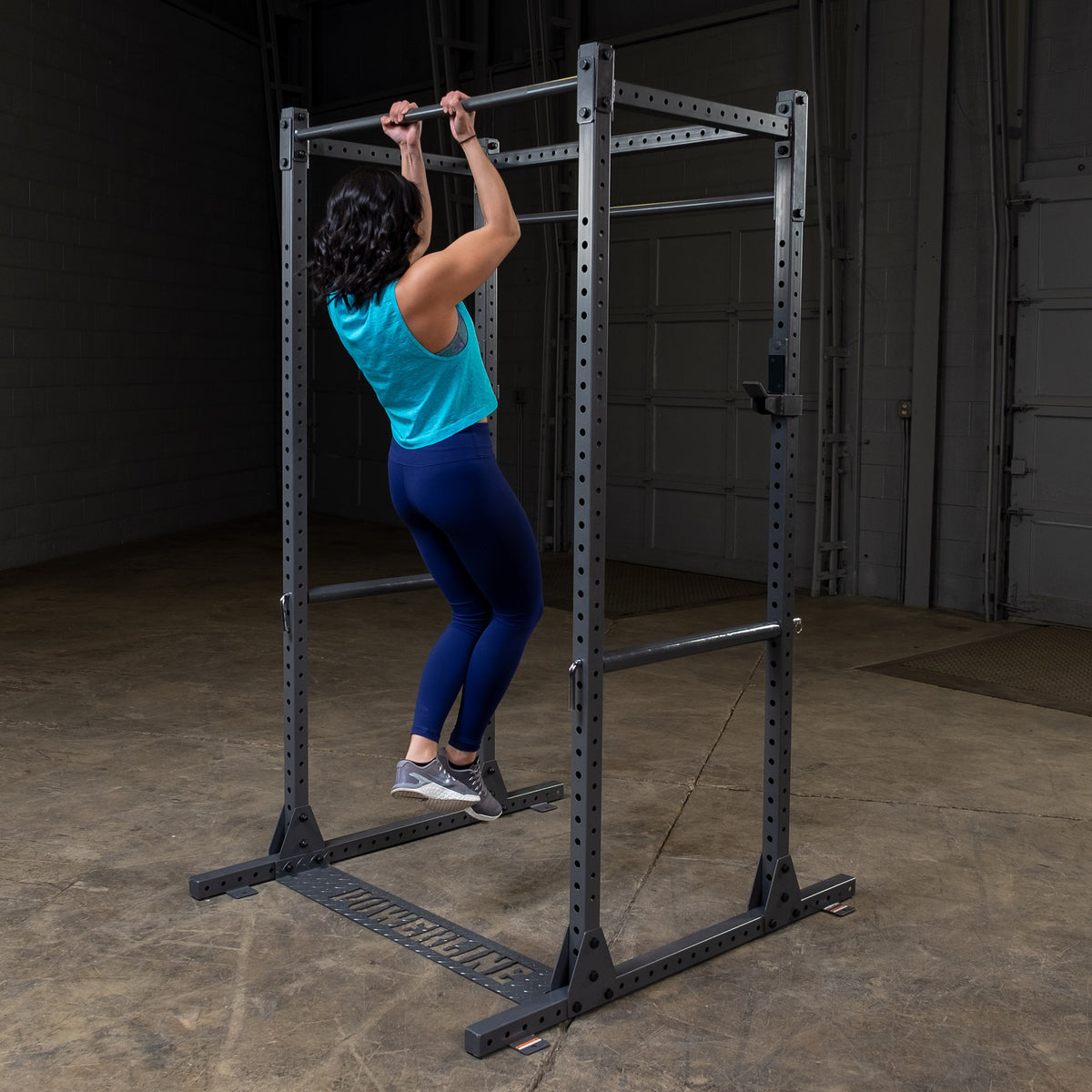 Woman doing a chin-up inside the Powerline PPR1000X Full Cage Power Rack